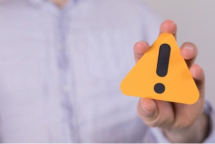 看護師が転職サイトを複数利用する際の注意点を示すイメージとして、警告マークを持つ人物の写真