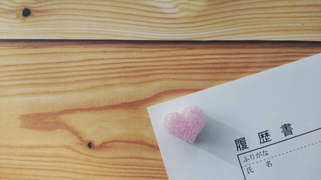 履歴書の上にハートのクリップが置かれた写真。丁寧に準備した履歴書で採用担当者に好印象を与えるイメージ