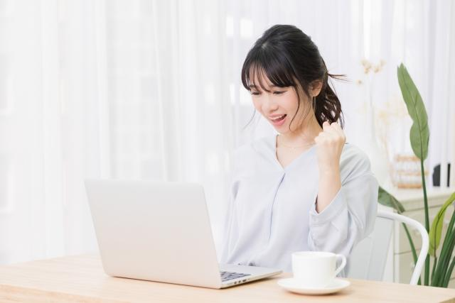 未経験から産業保健師を目指して努力を重ね、パソコンの前で喜ぶ女性のイメージ