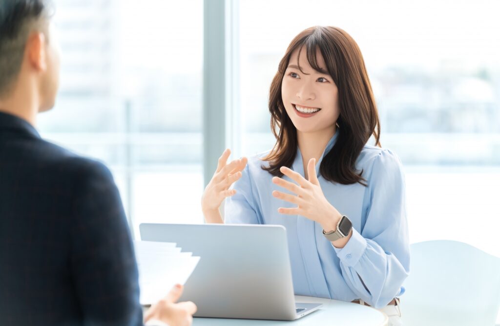面接で話をする笑顔の女性のイメージ。看護roo!を利用して1年目で転職した看護師の体験談を表現