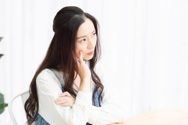 顎に手を当てて考え込む女性。アートメイクをしたらMRI検査は受けられないのか不安に思う様子を表した写真