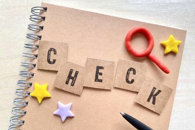 ノートの上に“CHECK”の文字と虫眼鏡が置かれた写真。MRI検査前に確認すべきことをイメージした構成