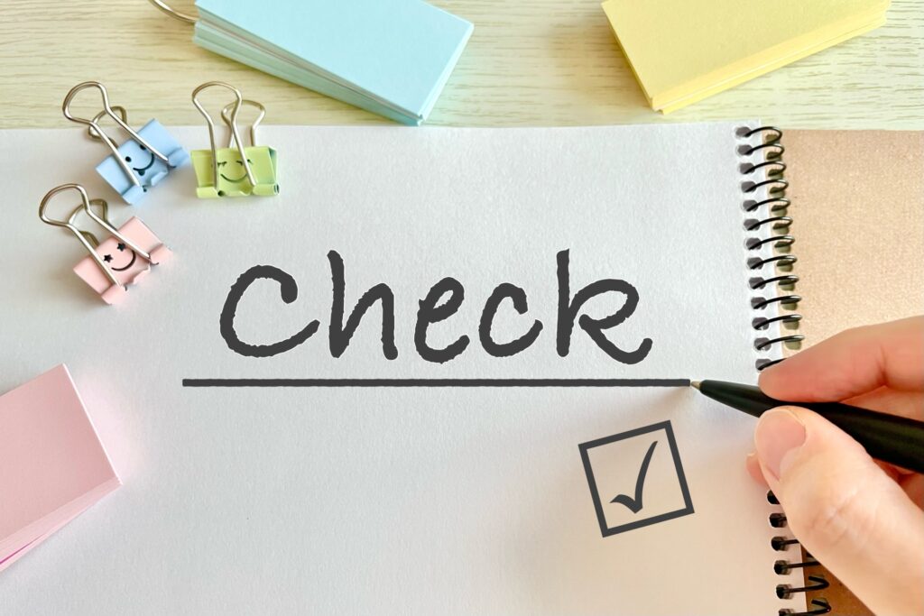 チェック項目を確認するノートとペン(更新なしを伝えるテンプレ)